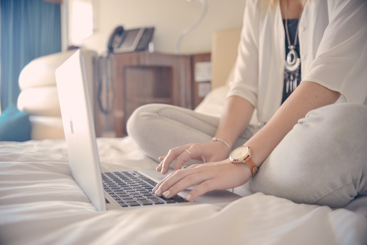 Kobieta na łóżku pisząca na laptopie