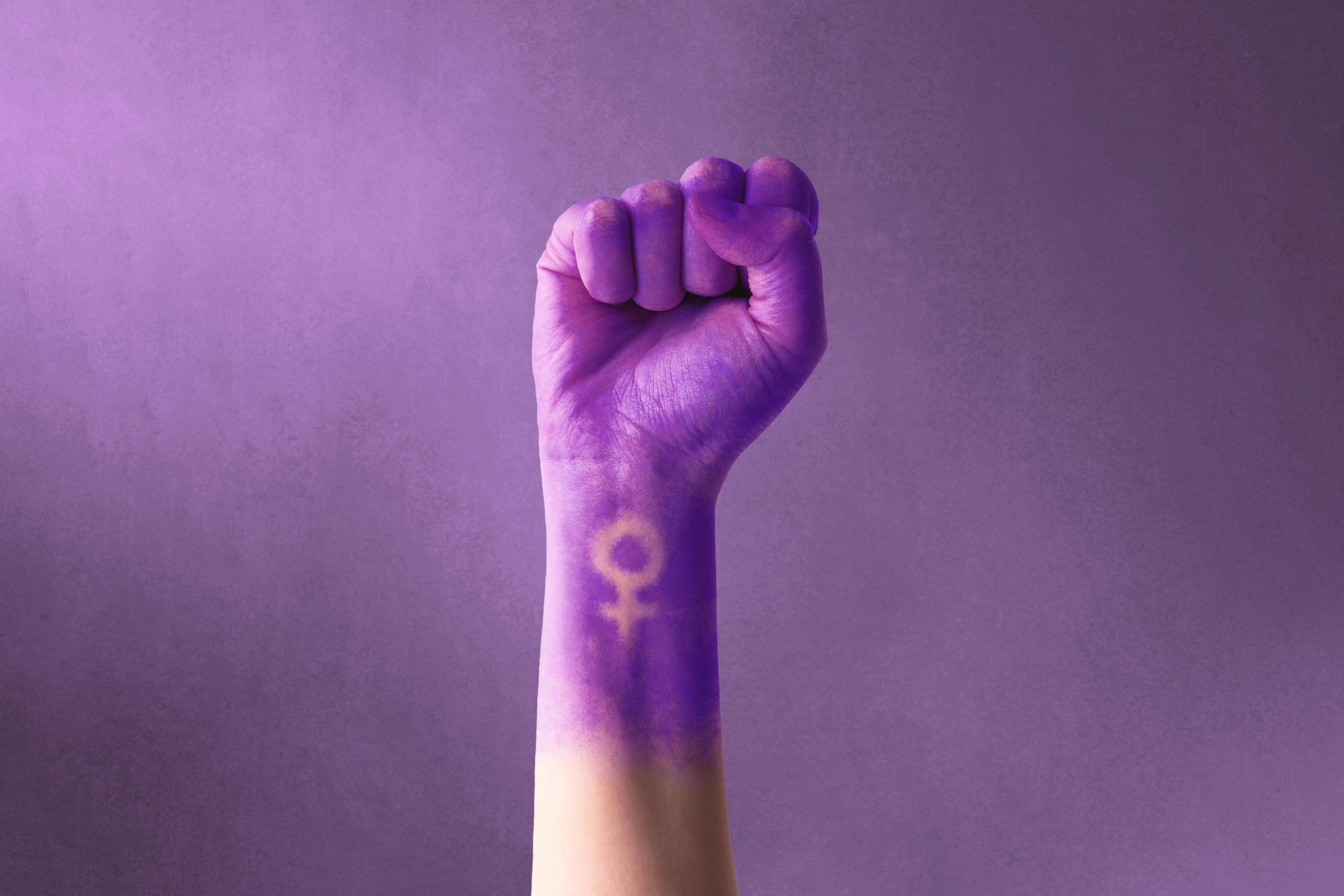 Ręka pomalowana na fioletowo z narysowanym znakiem płci żeńskiej (Foto. Canva Pro)