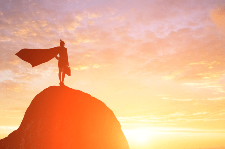 Kobieta w pelerynie Supermana stoi na szczycie góry