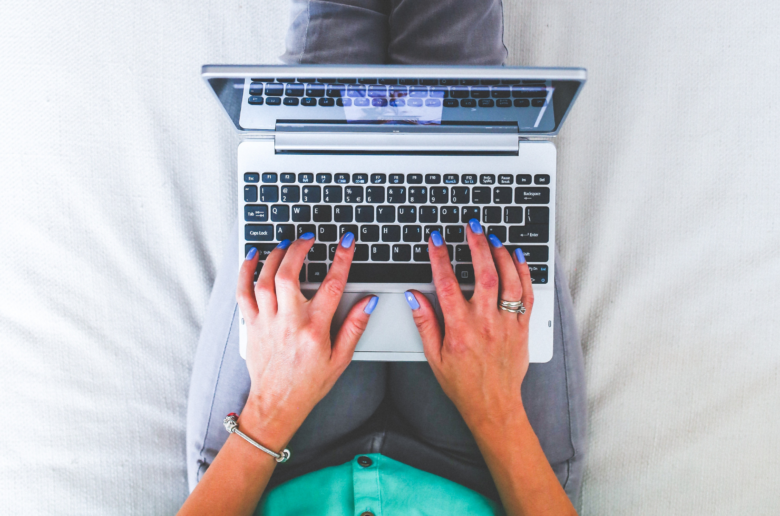 Kobieta siedząca na łóżku z laptopem na kolanach