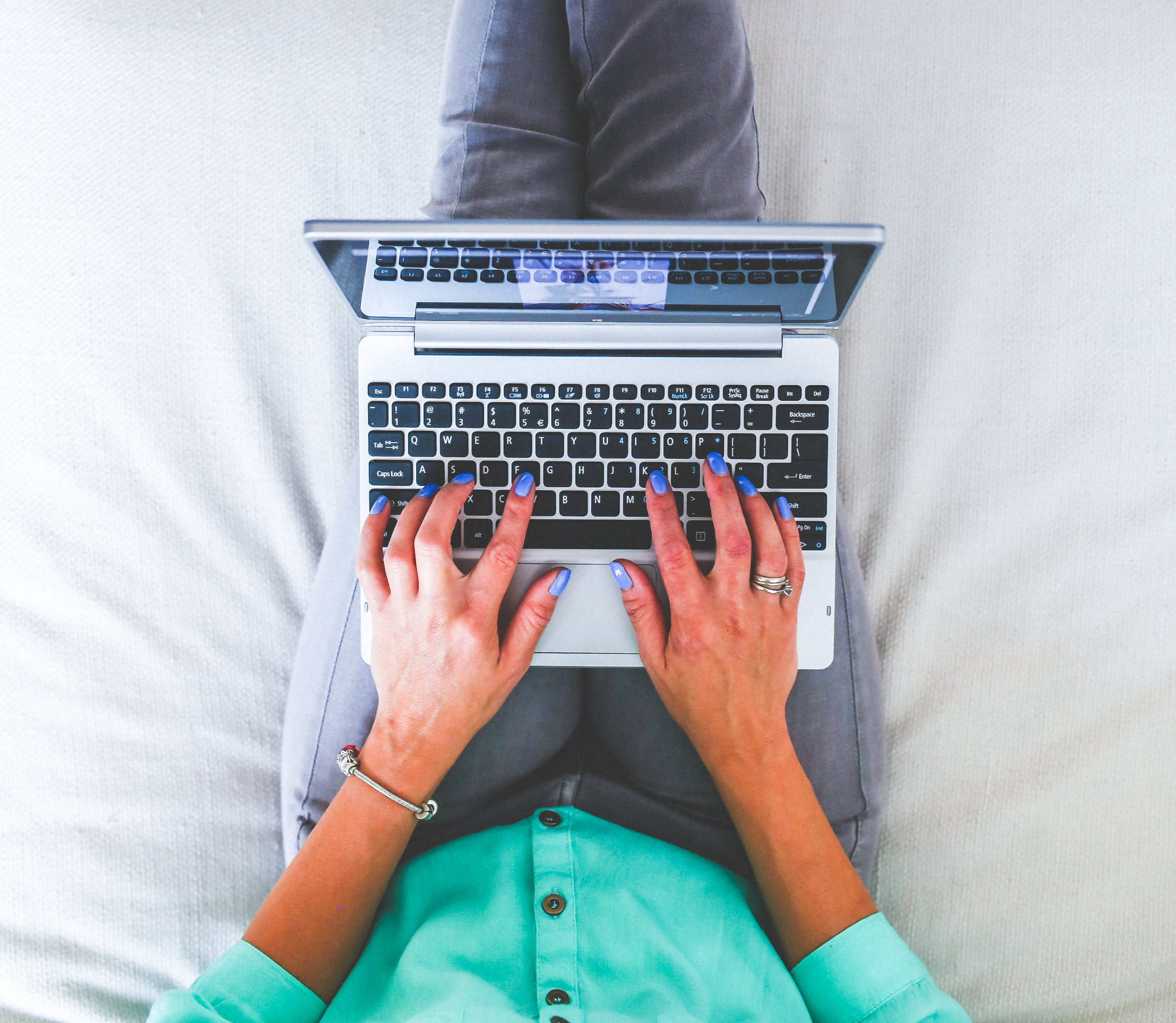 Kobieta siedząca na łóżku z laptopem na kolanach