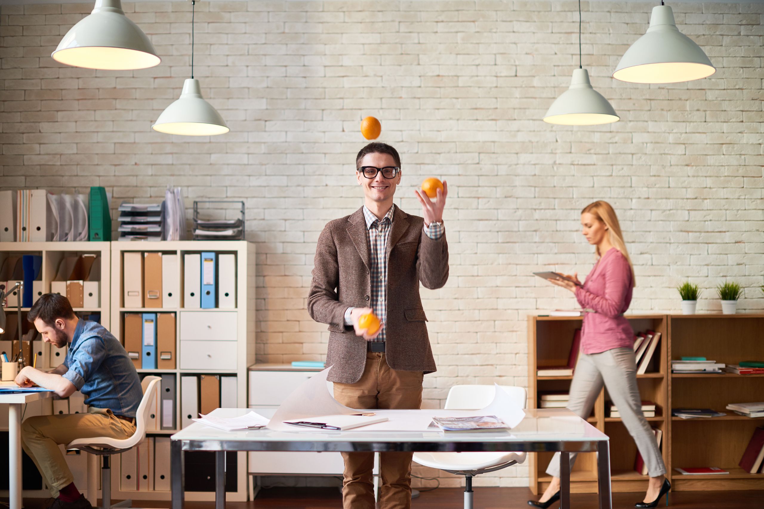 Mężczyzna żonglujący pomarańczami w biurze (Foto. Canva Pro)