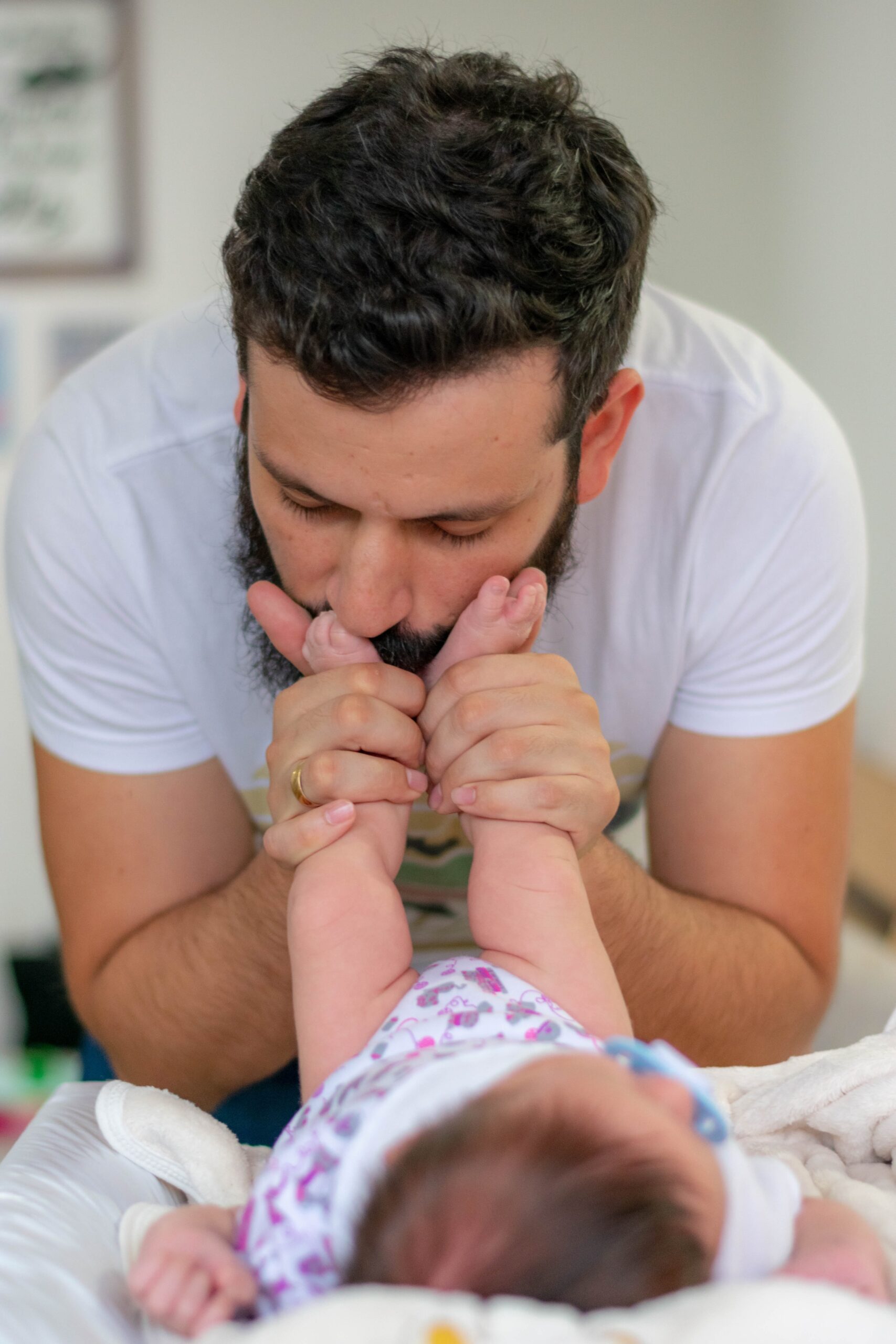 Tata całuje stopy swojego dziecka, niemowlaka