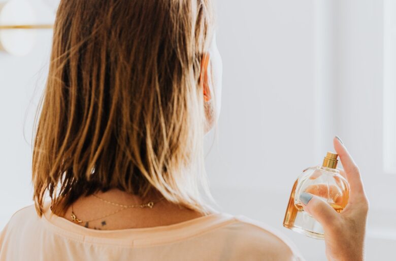 Kobieta psikająca się perfumami (advertorial)