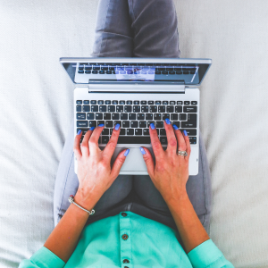 Kobieta siedząca na łóżku z laptopem na kolanach