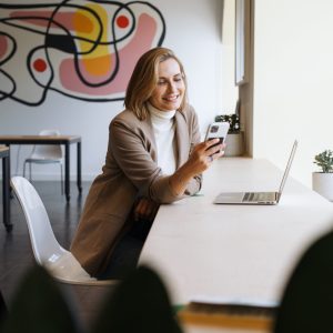 Kobieta przy komputerze, z telefonem w ręku | wirtualna asystentka